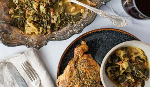 collard greens on silver plate with a dinner plate of roasted chicken, collard greens, and red wine on the side