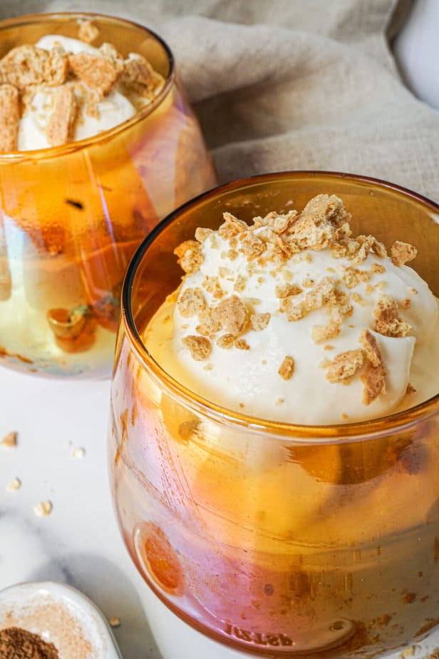 pumpkin pie overnight oats in a orange glass jar with whipped cream and crushed graham crackers on top